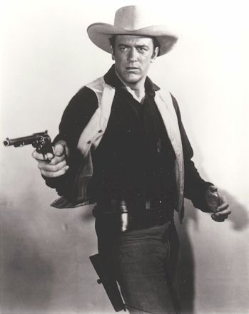 Photo of James Arness with cowboy hat and a gun in hand