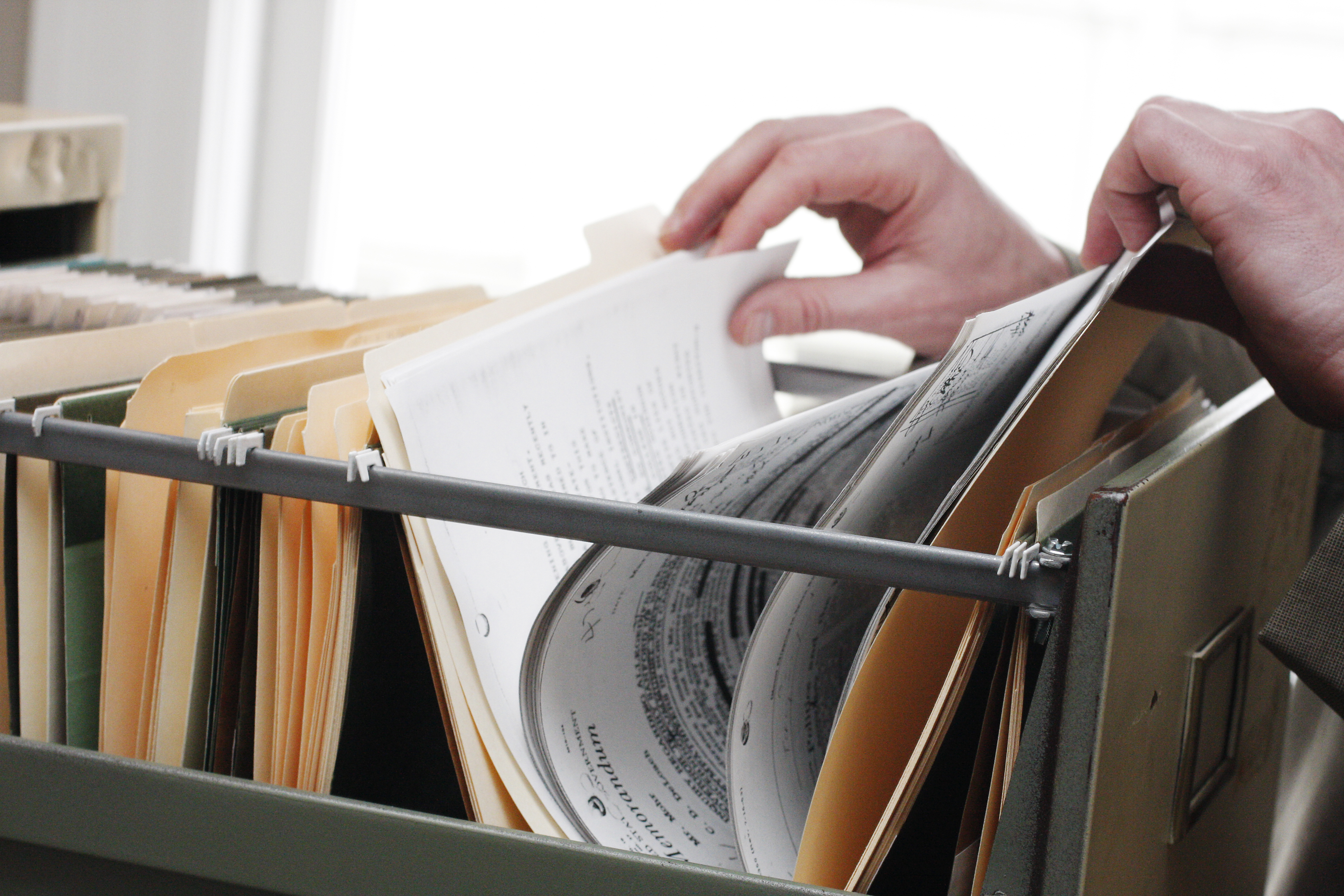 A hand searching in file cabin
