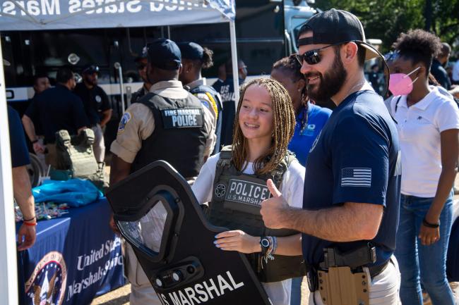 Deputy U.S. Marshal with a child holding a shield during…