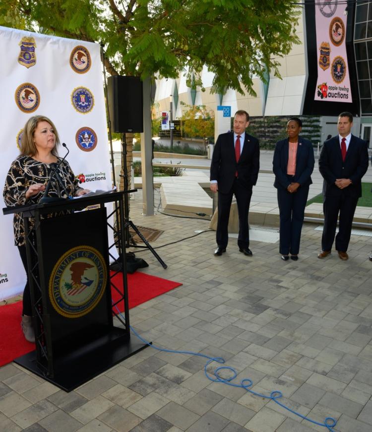 A female in front of podium and three people standing there